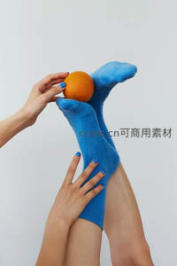 蓝色袜子脚趾夹橙子的手部互动特写