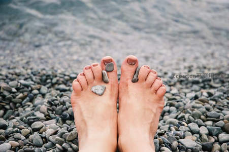 海边鹅卵石上摆放小石子的双脚