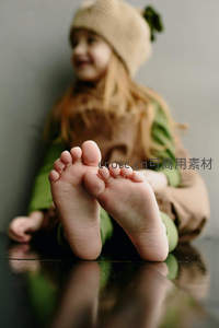 小女孩赤脚坐在光滑地板上