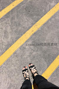 俯拍视角下，绑带凉鞋与黄色标线的几何美感