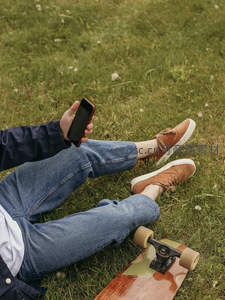 草坪上滑板少年，手机在手享受悠闲户外时光