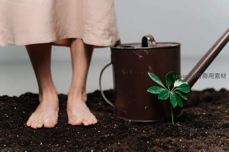 赤足立于泥土旁绿植与浇水壶的生机