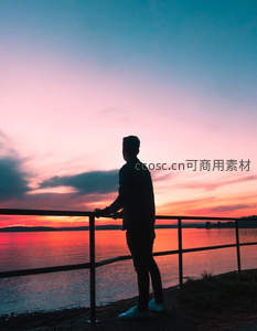 湖畔栏杆旁凝望落日的身影
