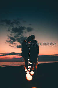 海岸日落，情侣相拥漫步灯光小径