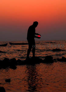 海边拾贝者手捧夕阳