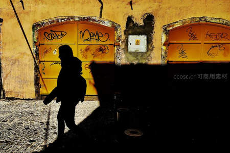 街头涂鸦墙前的行人剪影