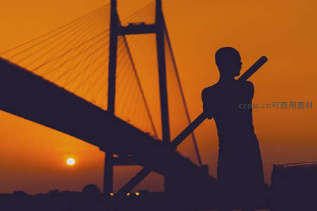 工人剪影在大桥旁扛工具劳作