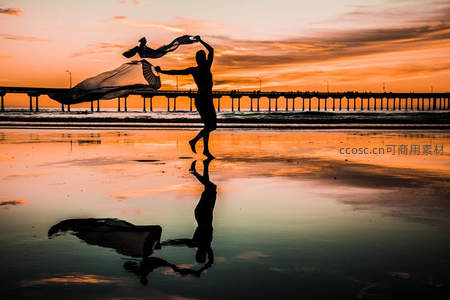 沙滩舞者飞扬纱巾，夕阳倒影如梦似幻