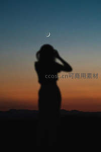 女子仰望新月剪影映衬晚霞