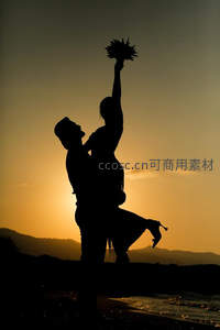 夕阳海滩上情侣托举浪漫瞬间