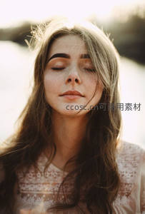 闭目享受阳光的长发女子