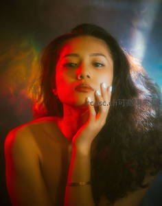 红光映照卷发女子，手托脸颊神情迷离