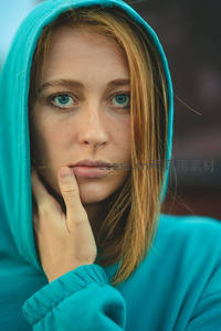 蓝帽衫少女手托下巴，清澈蓝眸直视前方