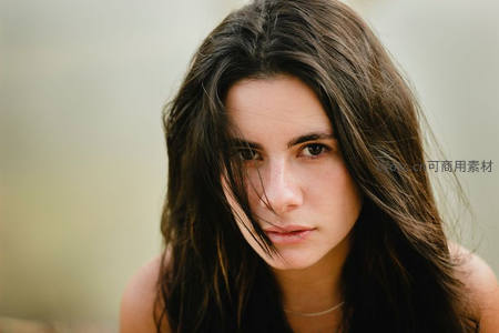 风中凌乱长发，自然光下女子沉静凝望镜头
