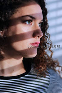 光影交错下卷发女子侧颜特写