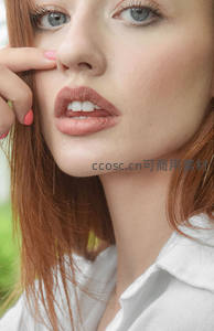 红发女子轻触面颊的温柔瞬间