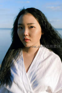 海边白衣女子凝望远方，海风拂动长发