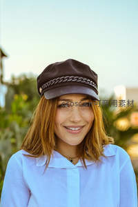 戴帽女孩微笑户外，蓝天绿植相伴