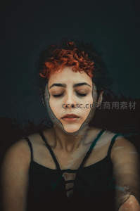 红发女子闭目沉思，面部轮廓若隐若现