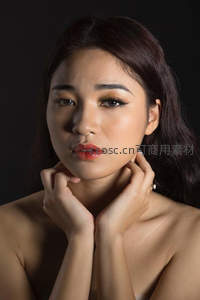 黑背景下双手托颈的女性