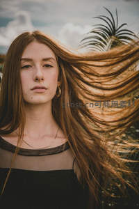 棕发飞扬女子热带背景神情沉静