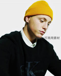 黄帽青年低头沉思，简约穿搭显文艺范