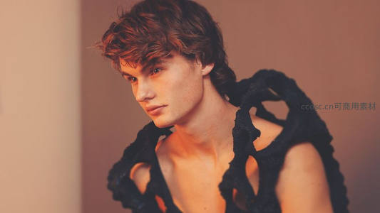 卷发青年身着黑色镂空服饰凝视前方