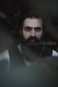 浓密胡须男子穿透绿叶凝视