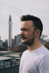 城市天台上的男子，背景高楼林立云层密布