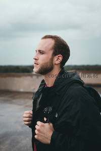 屋顶上的背包客，拉紧外套迎风远望城市