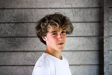 卷发少年靠墙侧身回眸凝视