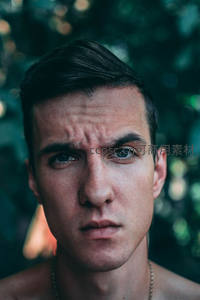 绿意背景下的深邃男性特写