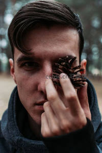 森林中男子手持松果遮眼