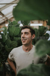 温室中的微笑青年与绿植相伴