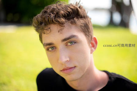 草地上的卷发少年凝视镜头