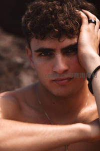 阳光下卷发青年手抚额头特写