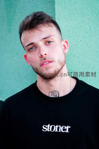 绿墙前穿黑T恤带鼻环的时尚青年