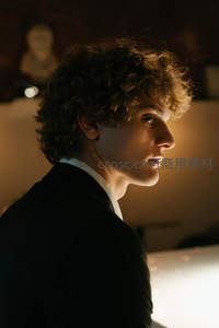 侧颜优雅的卷发青年，暖光勾勒轮廓