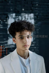 黑砖墙前穿白西装的少年