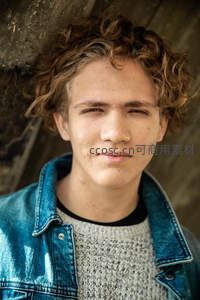 卷发少年倚墙微笑