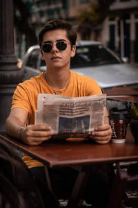 街头咖啡馆戴墨镜读报的青年
