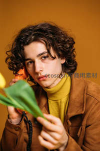 卷发少年手持电话与郁金香凝视镜头