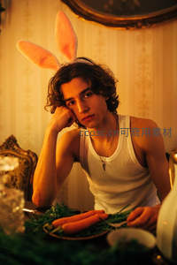 戴兔耳的年轻人坐在餐桌前托腮沉思