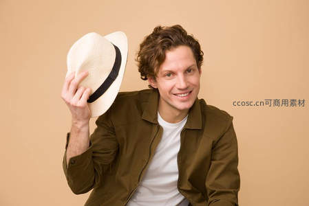 卷发男子微笑持帽，休闲时尚造型