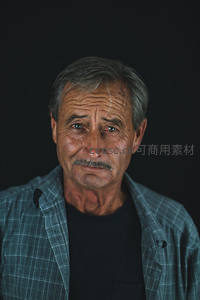 深色背景前沉思的老者，眼神充满故事