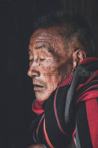 侧脸老人闭目沉思，红黑披肩显庄重