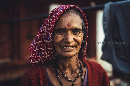 头巾老妇微笑迎人，额头红点添风情