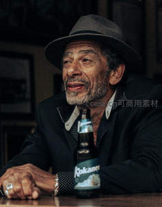 戴帽男士酒吧品酒，沉思神情尽显岁月故事