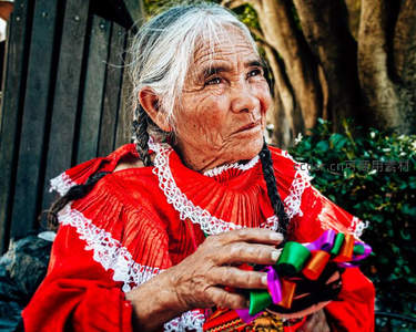 身着传统红衣的老妇人手捧彩带