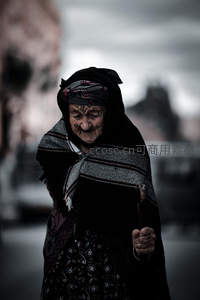 黑衣老妪拄杖前行，阴郁天空下的孤独身影